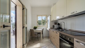 A modern kitchen with a dining area, a built-in oven, and a window.