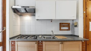 Una cocina con estufa a gas, lavamanos y armarios blancos.
