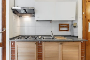 A kitchen with a gas stove, sink, and white cabinets.