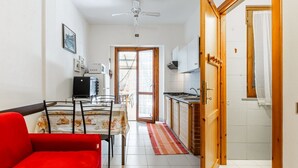 Una cocina compacta con comedor, un sofá rojo y un ventilador de techo.