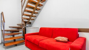 Una escalera con escalones de madera y un sofá rojo con un cojín estampado.