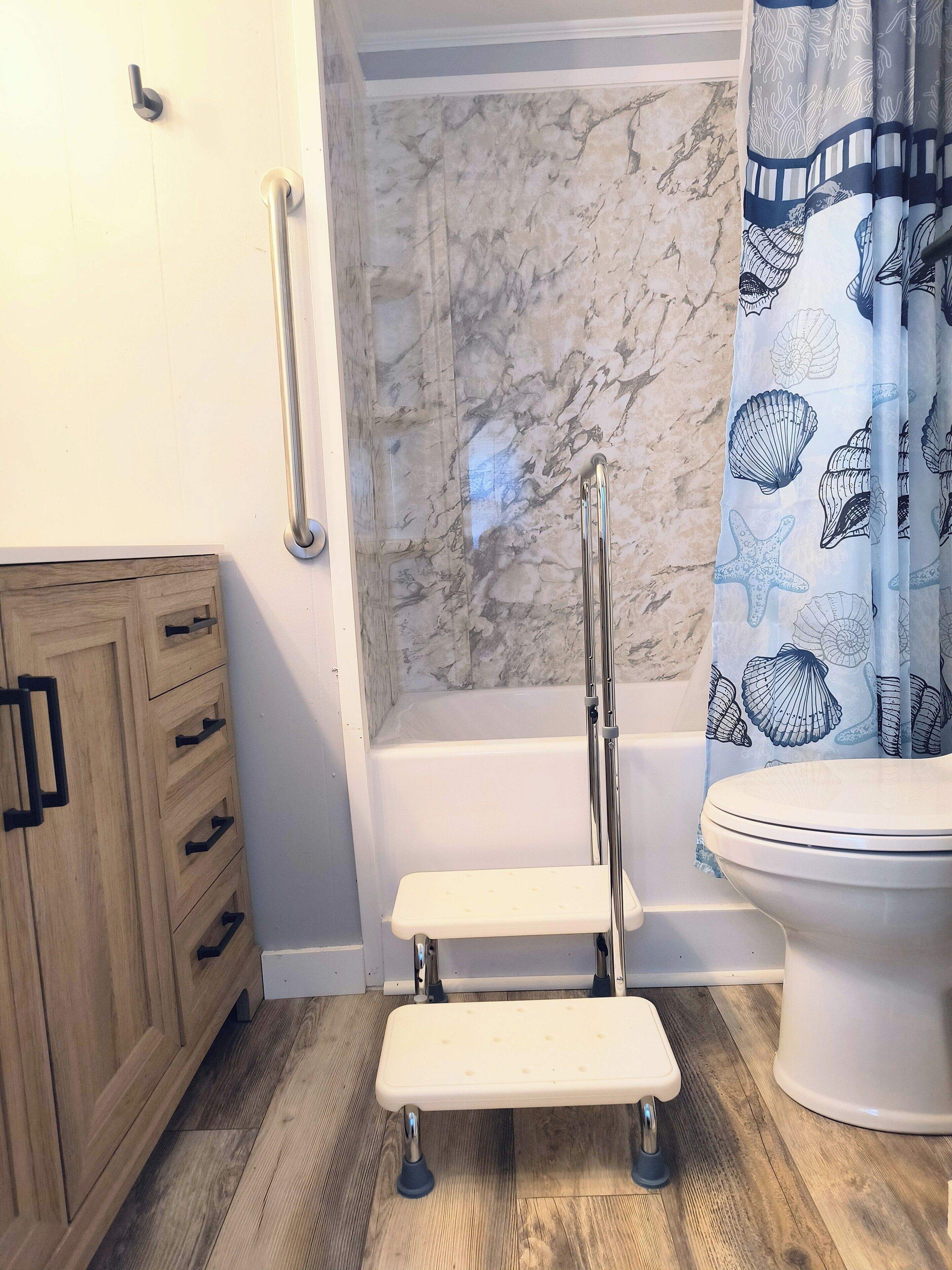 Une salle de bain avec un mur en marbre, une baignoire, des toilettes, un meuble en bois et un siège de douche.