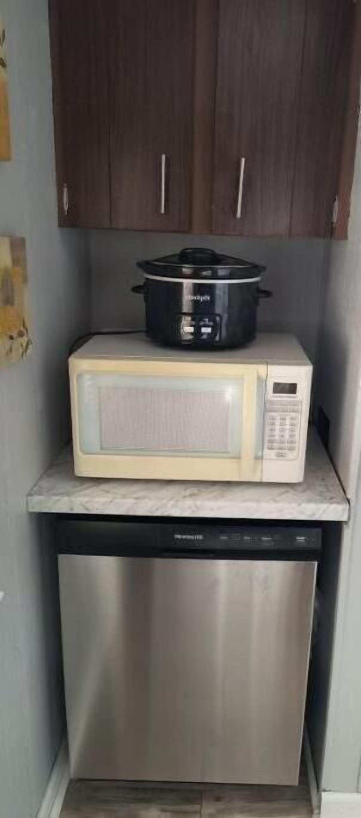 Une cuisine compacte équipée d’un four à micro-ondes, d’une mijoteuse et d’un lave-vaisselle.