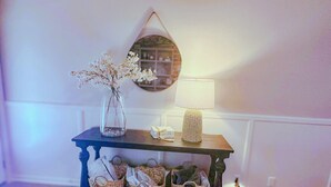Ein kleiner Tisch mit Blumen in einer Vase, einer Lampe und Körben auf einer Holzkonsolle.