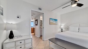 Un dormitorio con cama, mesita de noche, lámpara y un cuadro en la pared.