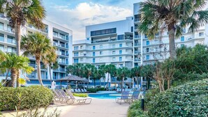 Un hotel con varias plantas, piscina y palmeras.
