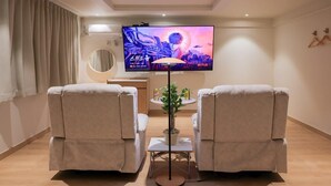 A room with two reclining chairs, a small table with a plant, a TV mounted on the wall, and a round mirror. - Ace Hotel by Anook Daejeon Yuseong (Daejeon)