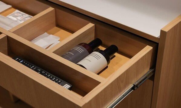 A wooden drawer with compartments, one of which contains two bottles and a keyboard.