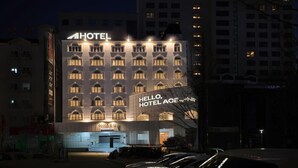 A hotel building with illuminated signage, a parking lot, and surrounding high-rise buildings. - Ace Hotel by Anook Daejeon Yuseong (Daejeon)