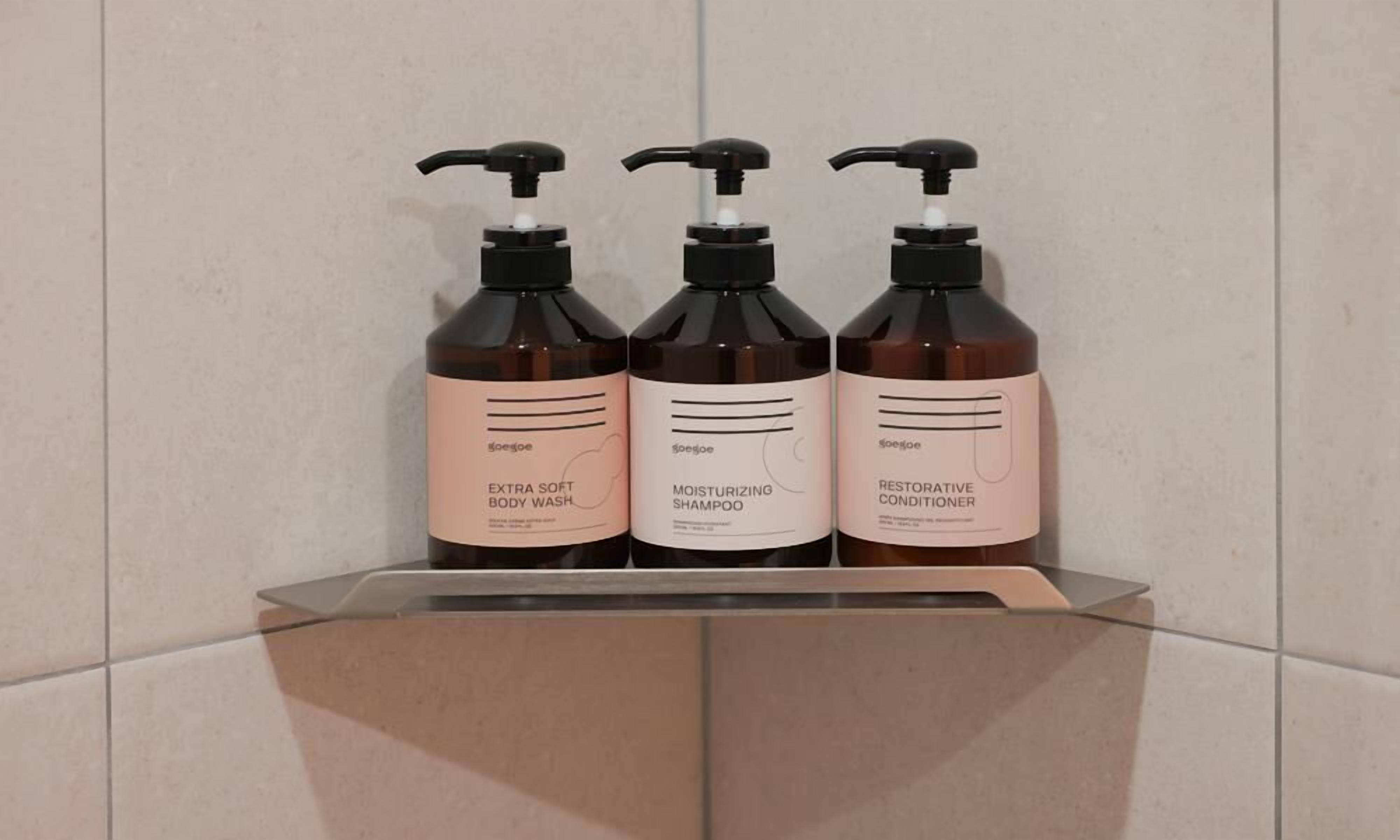 Three bottles of body wash, shampoo, and conditioner on a shelf.