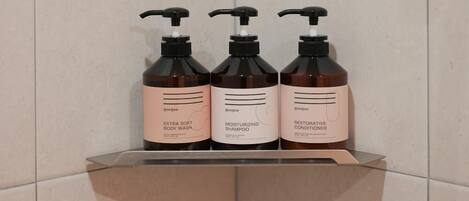 Three bottles of body wash, shampoo, and conditioner on a shelf.