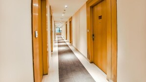 Ein langer, schmaler Hotelkorridor mit Holztüren an beiden Seiten und Teppichboden.