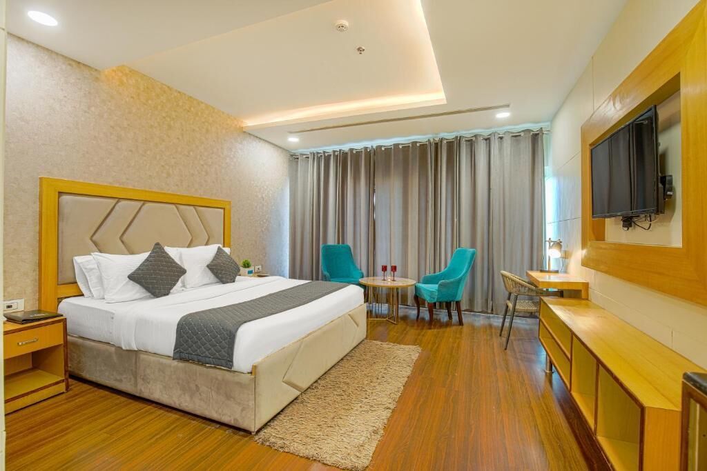 Une chambre d’hôtel équipée d’un lit, d’un bureau, d’une télévision et d’un coin salon avec des fauteuils.