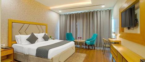 Une chambre d’hôtel équipée d’un lit, d’un bureau, d’une télévision et d’un coin salon avec des fauteuils.