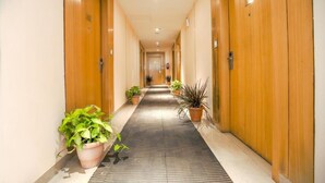 Ein Hotelgang mit Holztüren, Topfpflanzen und einem gefliesten Boden.