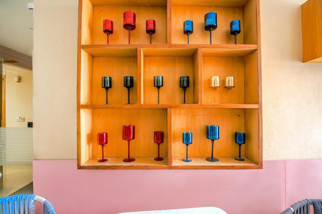 Una estantería de madera con varios vasos de vino de colores.