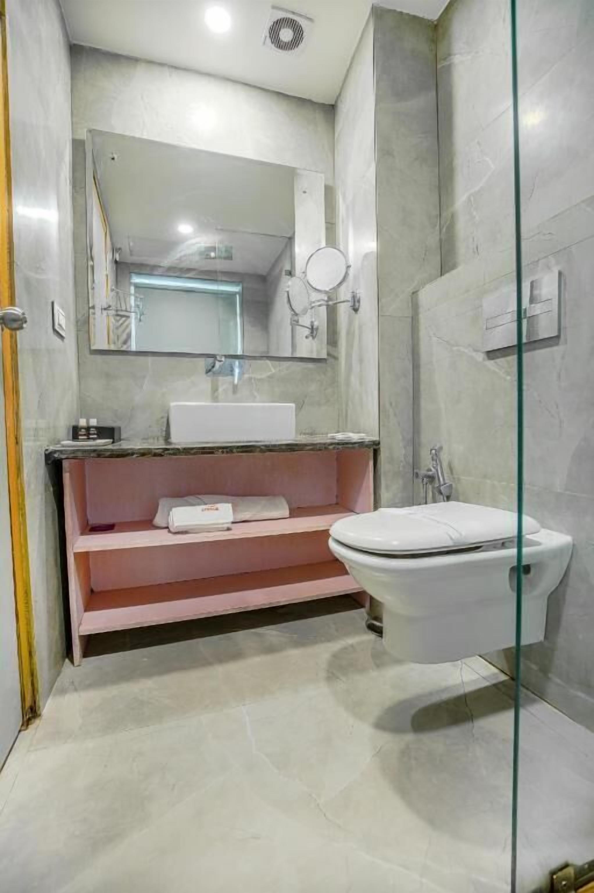 Une salle de bain moderne avec un meuble-lavabo en marbre, une cabine de douche en verre et des toilettes blanches.