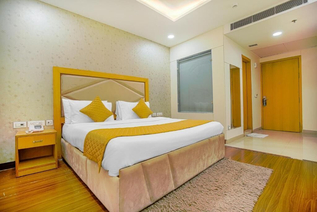 Une chambre d’hôtel avec un grand lit, une table de chevet, un plancher en bois et une grande fenêtre.
