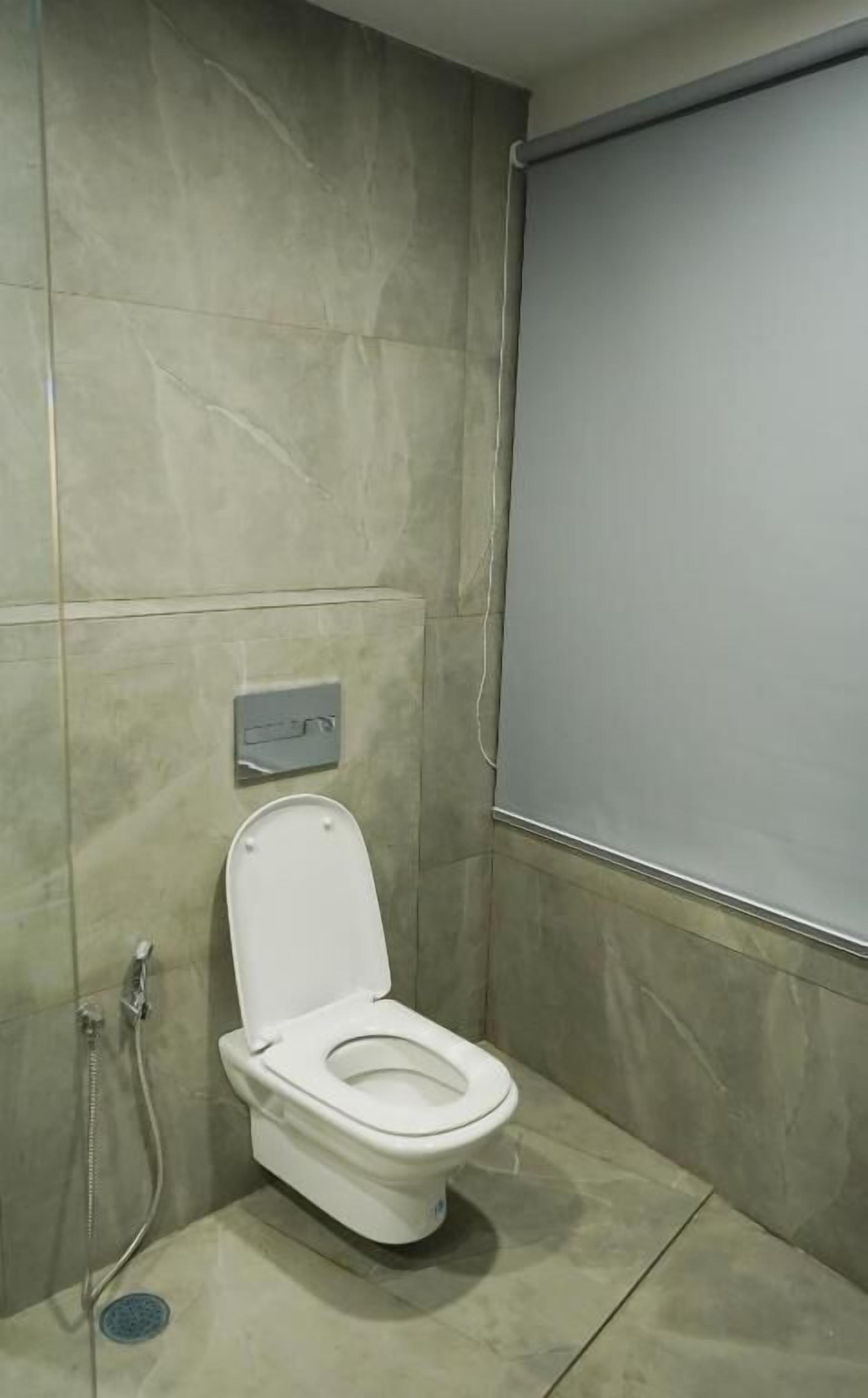 Een compacte, moderne badkamer met toilet, douche en een bedieningspaneel aan de muur.