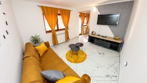 Un salon moderne avec un canapé, une table basse et un téléviseur à écran plat fixé au mur.