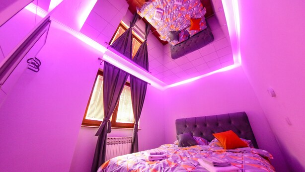 Une chambre à coucher avec un lit, des rideaux, un radiateur et une fenêtre.