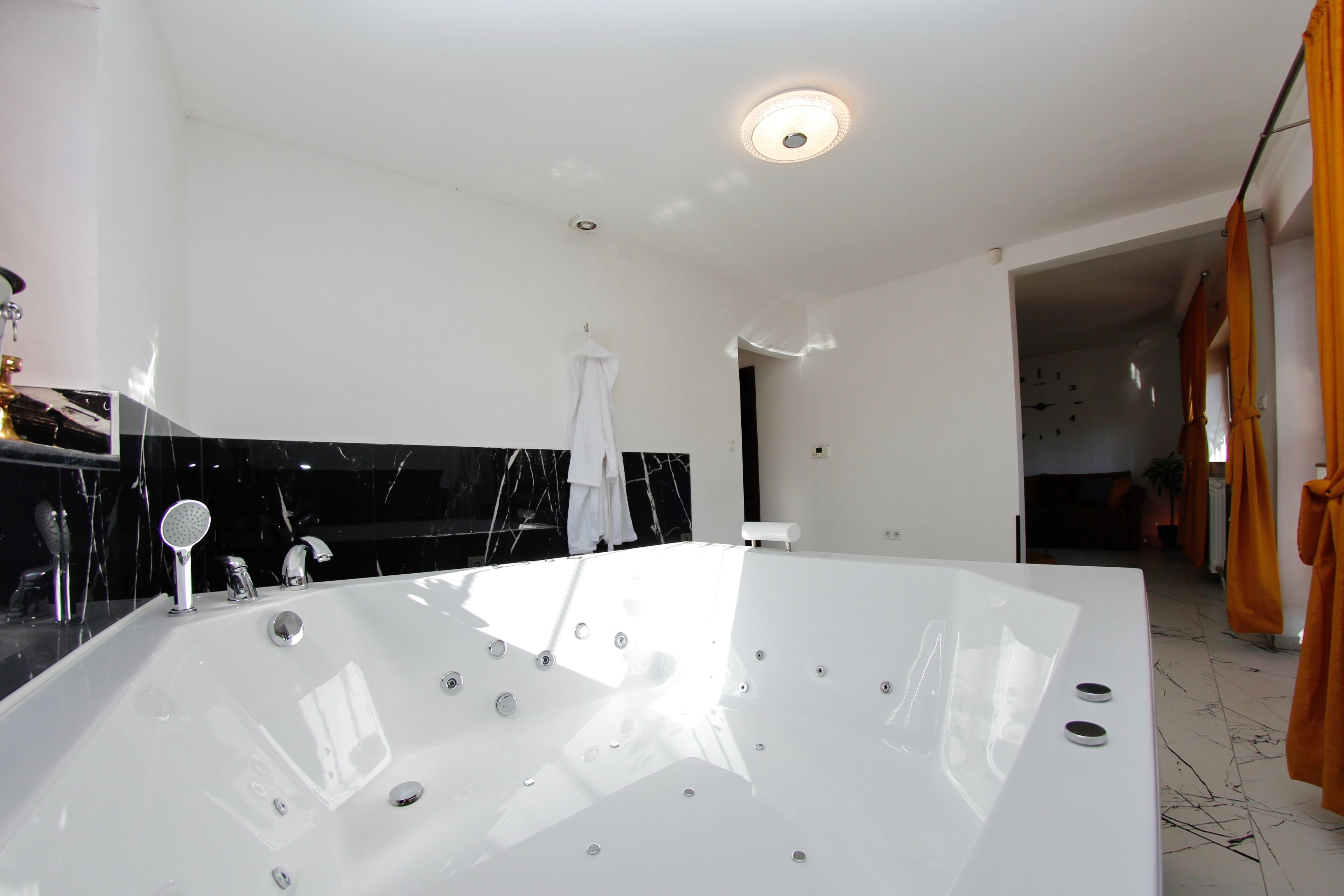 Un baño moderno con una bañera grande, una encimera de mármol negro y una toalla blanca colgada en la pared.