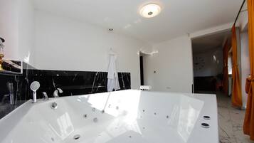 Un baño moderno con una bañera grande, una encimera de mármol negro y una toalla blanca colgada en la pared.