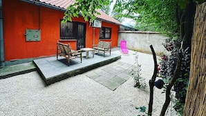 Une cour avec un bâtiment rouge, du mobilier d’extérieur et un petit espace jardin.