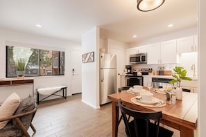 A modern kitchen with white cabinets, stainless steel appliances, and a dining area with a wooden table and chairs. - Park City Red Pine K2 with Community Amenities & Year Round Recreation! (Park City)