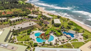 A resort with multiple swimming pools, a beach, and a mountainous backdrop. - Lagoon View Resort Retreat (Lihue)