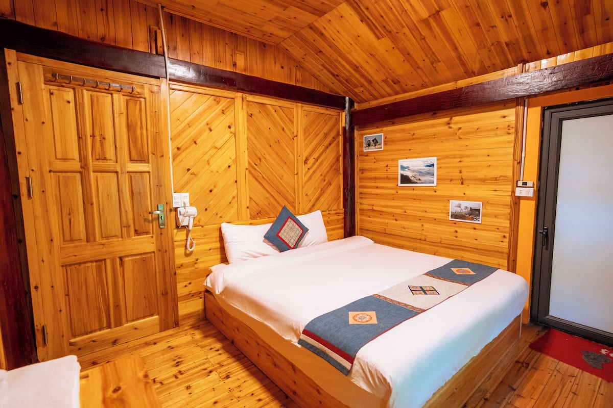 Ein Zimmer mit Holzwänden, einem Bett, einem Kleiderschrank und einer Tür.