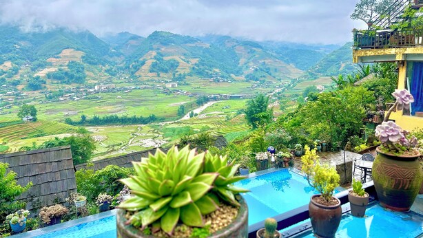 Un espace piscine agrémenté de plantes en pot, avec vue sur des champs en terrasses et des montagnes.