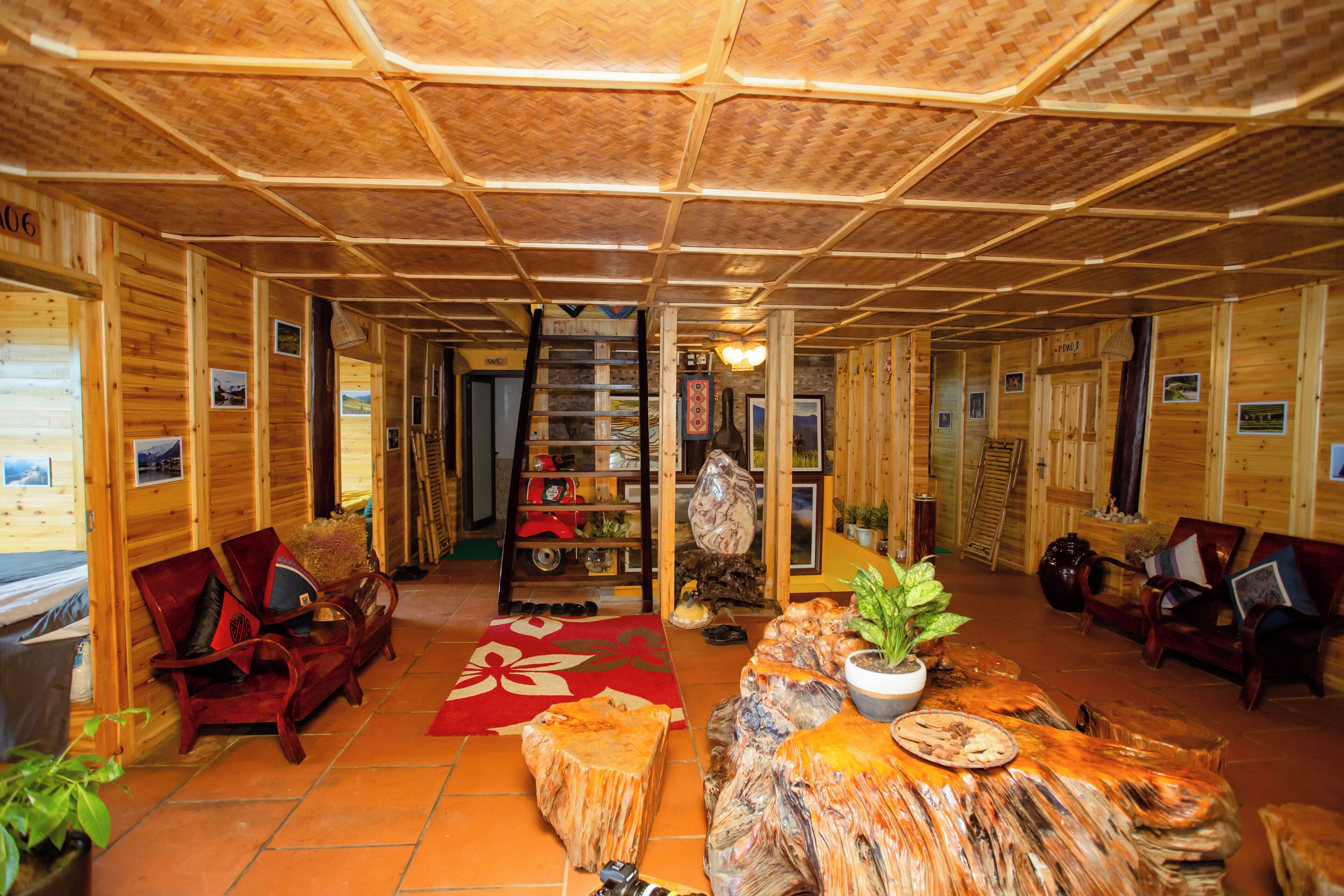 Un interior de madera con una escalera central, zonas de estar y una chimenea.