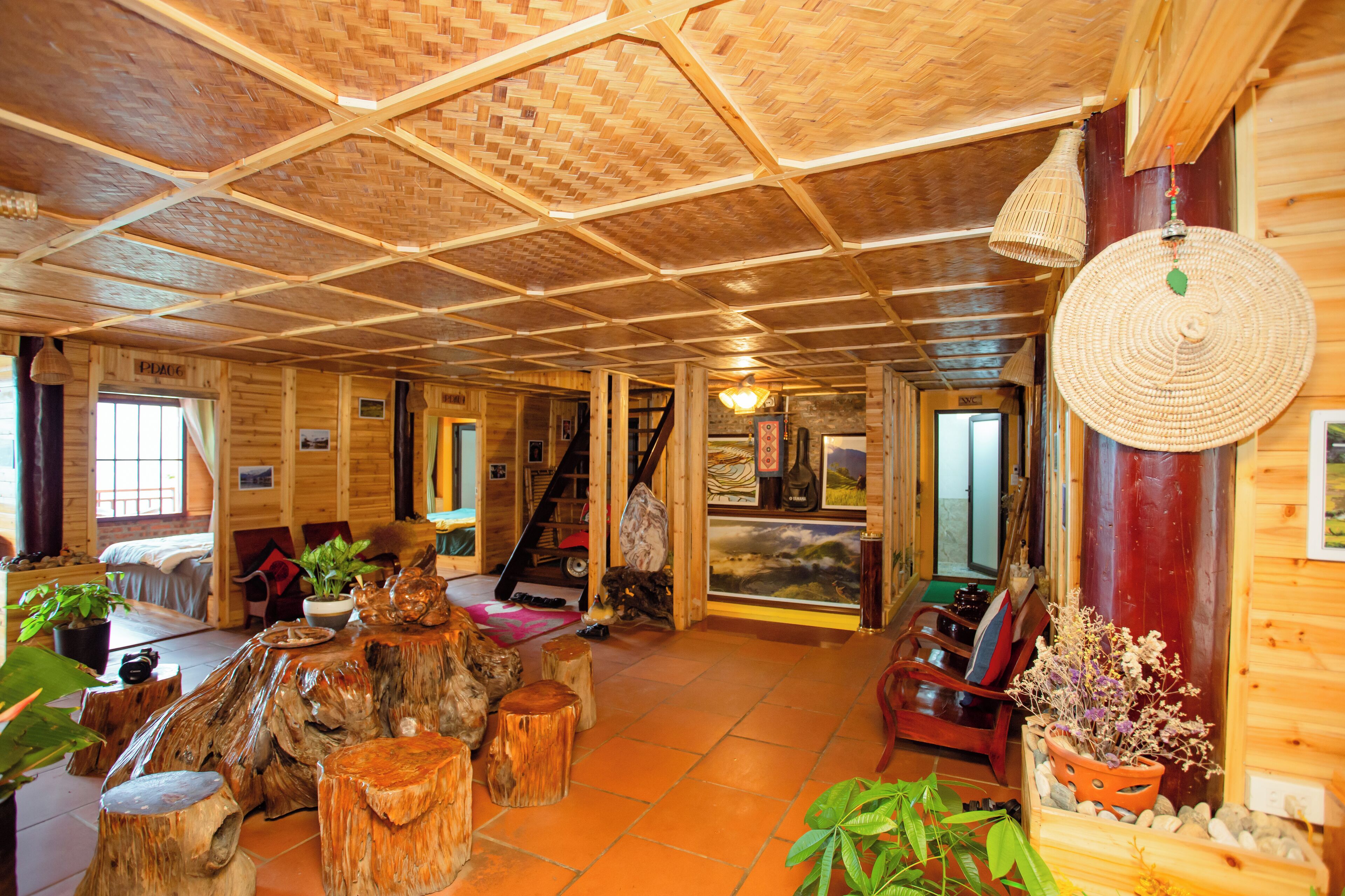 A wooden cabin interior with a high ceiling, rustic furniture, and a cozy fireplace.
