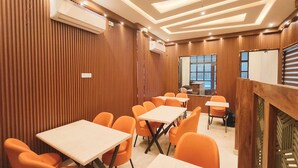 Un salón de conferencias con paneles de madera, sillas anaranjadas y mesas.