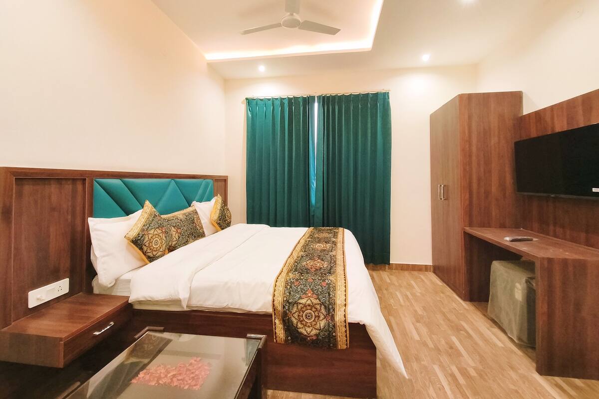 A hotel room with a bed, a TV, a desk, and a ceiling fan.