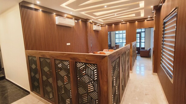Zona de recepción con un mostrador de madera, paneles decorativos en la pared e iluminación empotrada en el techo.