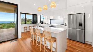 A modern kitchen with a large island, stainless steel appliances, and a view of the outdoors.