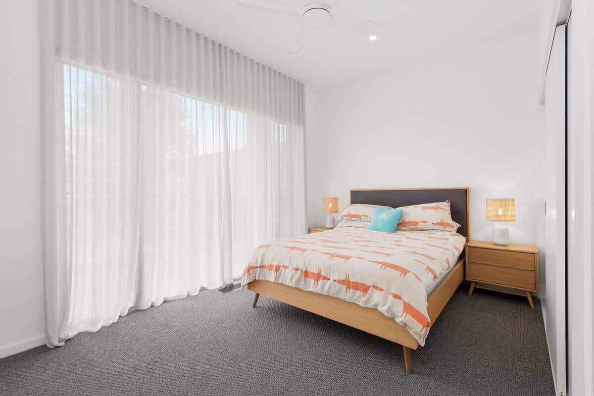 A bedroom with a bed, curtains, a nightstand, and a lamp.