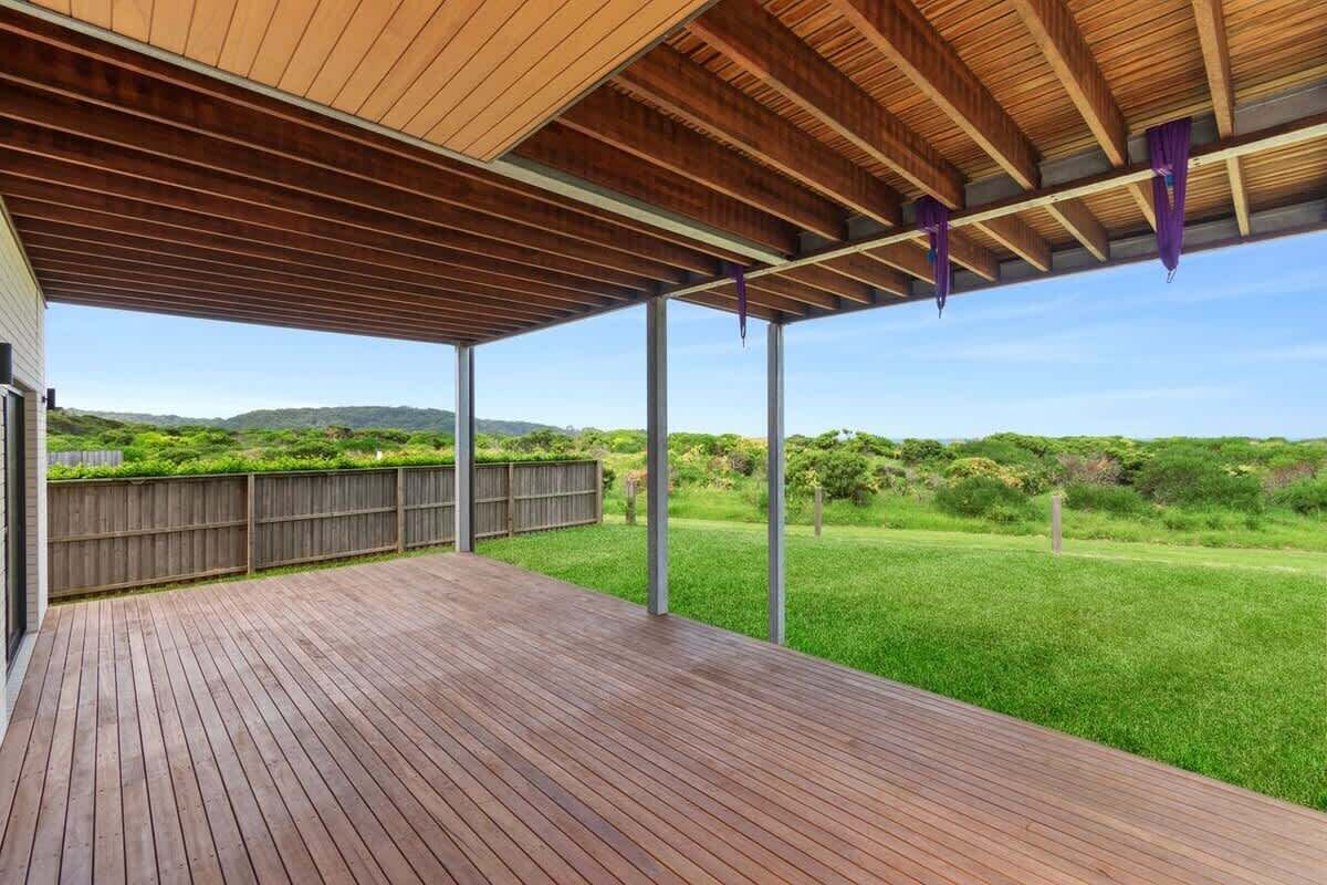 An outdoor wooden deck with a view of a grassy landscape and hills.