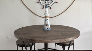 Una mesa redonda de madera con un detalle de timón de barco y una barandilla de cuerda.