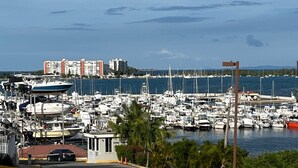 Un puerto deportivo con numerosas embarcaciones amarradas, un pequeño edificio y una vista distante de un paisaje urbano con edificios.