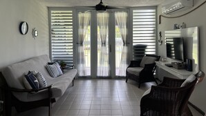Una sala de estar con sofá, sillas, ventilador de techo y televisor.
