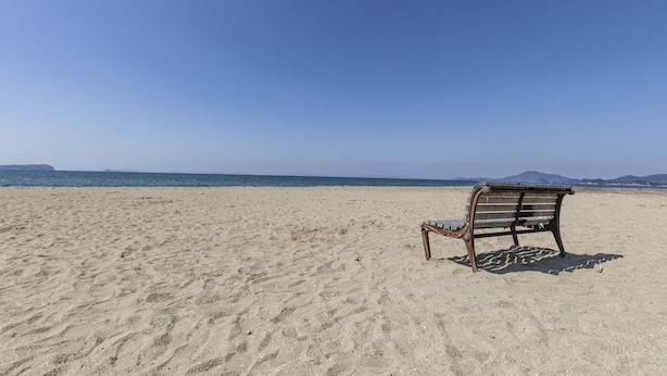 Una playa con un banco de madera mirando al océano.