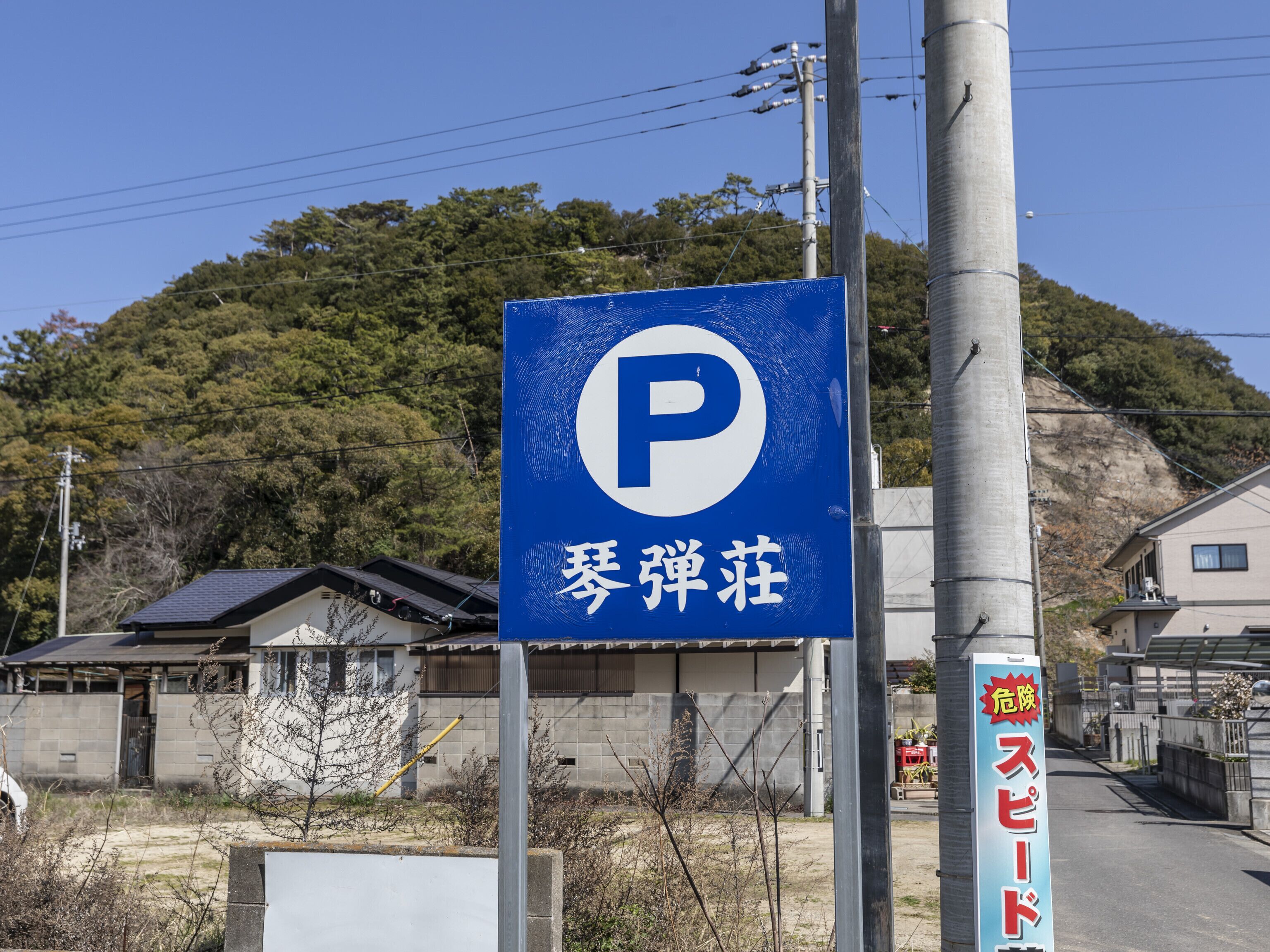 Señal de estacionamiento con una 'P' grande y caracteres japoneses, que indica una zona de aparcamiento.