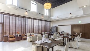 Una amplia sala de conferencias con sillas blancas, una mesa larga y una moderna lámpara de araña.