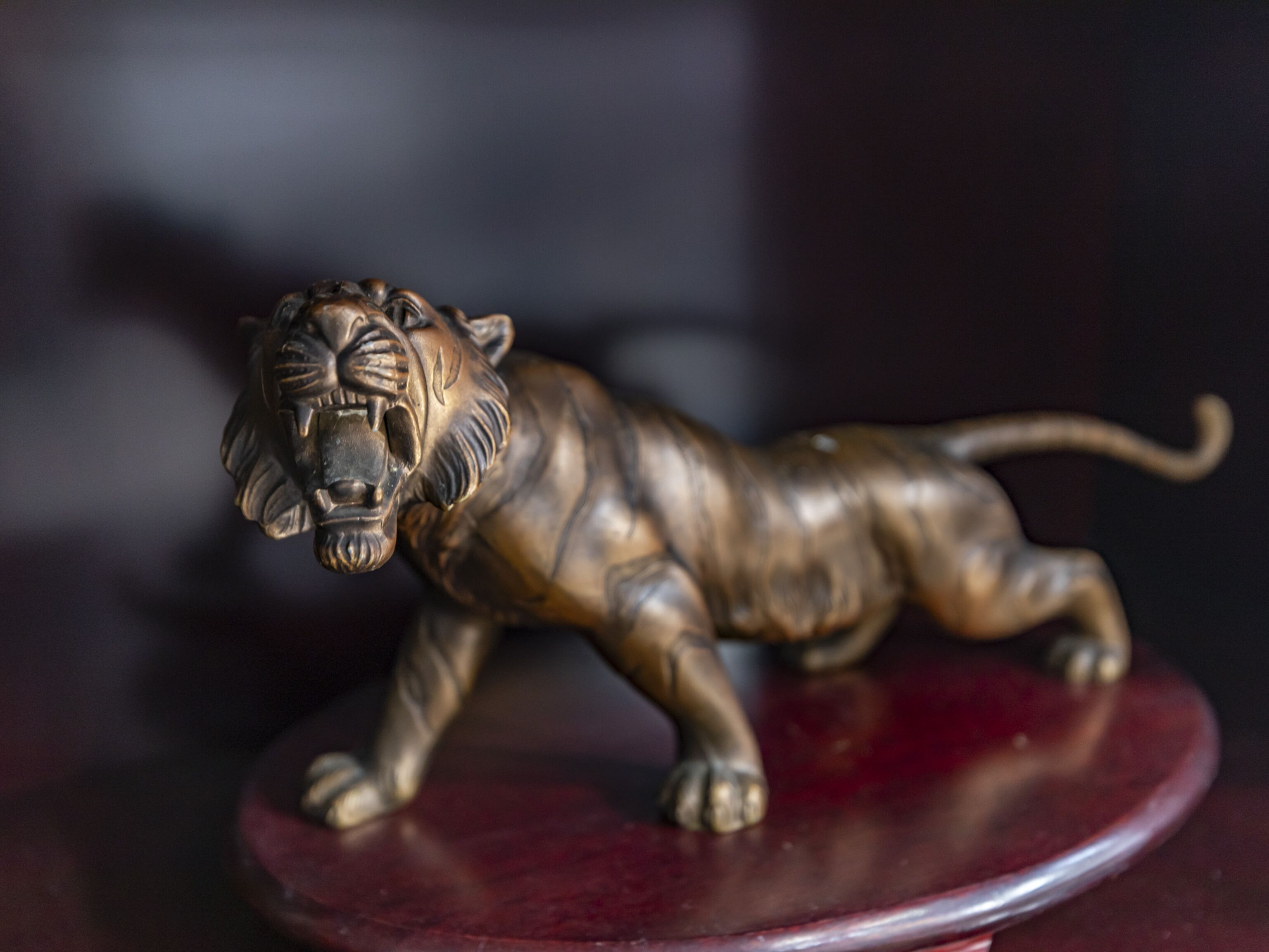 A bronze figurine of a tiger on a red base.