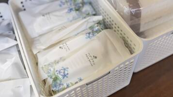 A storage area with white baskets containing folded items, some with floral patterns and text, and a plastic-wrapped item in the background.