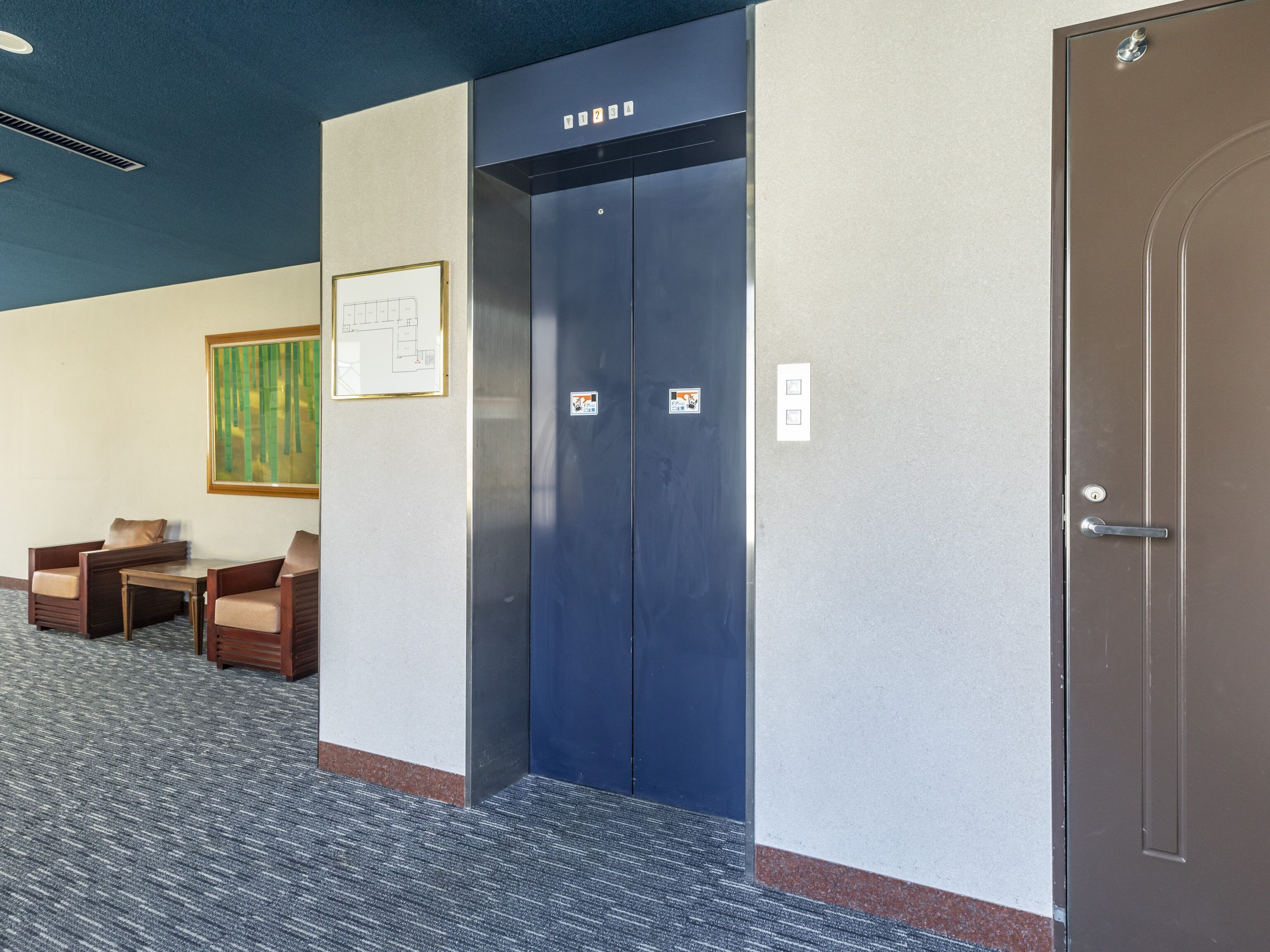 An elevator with a control panel, a door with a keyhole, and a wall-mounted sign.