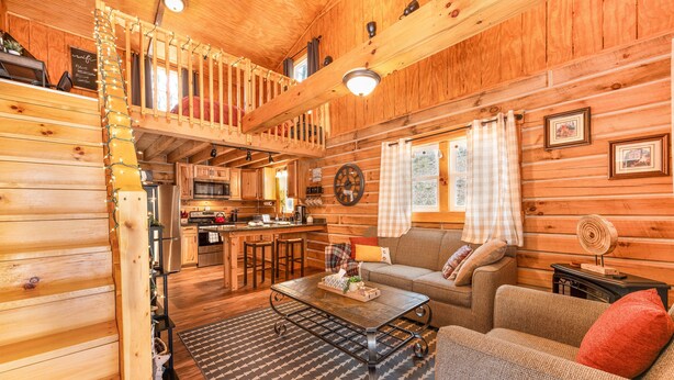 Ein gemütliches Blockhaus-Interieur mit Essbereich, Küche und Wohnzimmer mit Sofa und Couchtisch.
